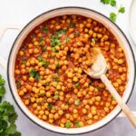 Thick and flavorful chana masala simmering on the stovetop with a wooden spoon.