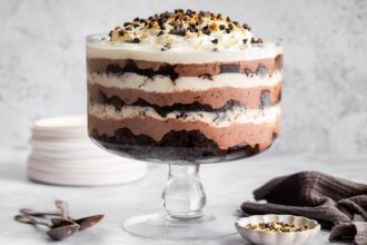 Assembled chocolate trifle showing layers of brownies, pudding, and whipped topping in a glass dish.