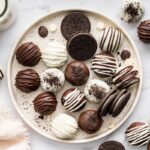 Platter of Oreo truffles topped with chocolate drizzle and Oreo crumbs.