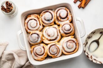 Protein cinnamon rolls in a square baking dish topped with an icing.
