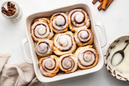 Protein cinnamon rolls in a square baking dish topped with an icing.