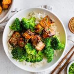 Teryaki salmon bites served on a plate with white rice and broccoli.
