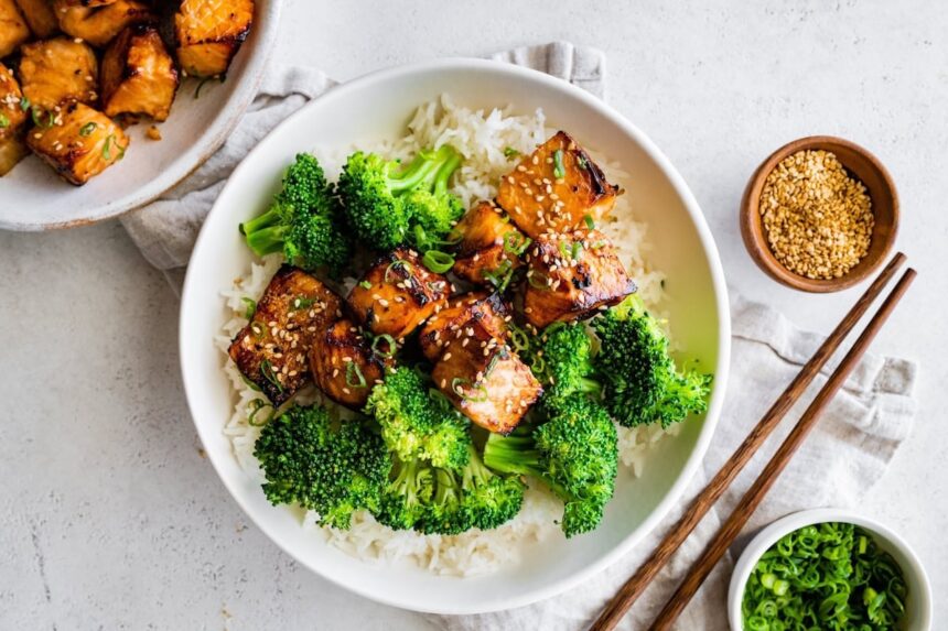 Teryaki salmon bites served on a plate with white rice and broccoli.