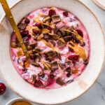 Close-up of chocolate cherry cheesecake yogurt bowl with crunchy toppings.
