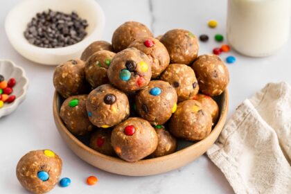 Bowl of monster cookie protein balls made with oats, peanut butter, chocolate chips, and M&M&rsquo;s.
