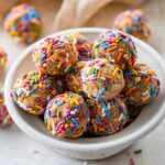 A bowl full of birthday cake protein balls with colorful sprinkles.