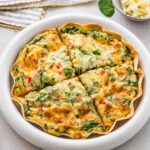 High-protein tortilla quiche sliced into wedges in white pie dish, ready to serve.