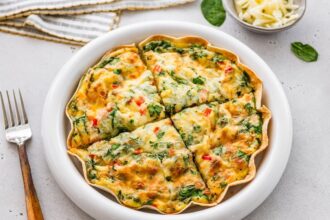 High-protein tortilla quiche sliced into wedges in white pie dish, ready to serve.