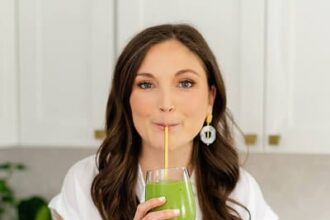 Woman (Brittany Mullins) wearing a white shirt and sipping a green smoothie.